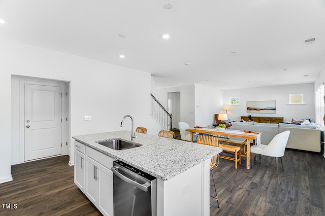 kitchen with stainless steel dishwasher, a sink, open floor plan, an island with sink, and dark wood-style floors