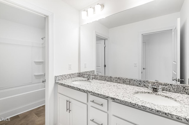 bathroom featuring tub / shower combination, double vanity, and a sink
