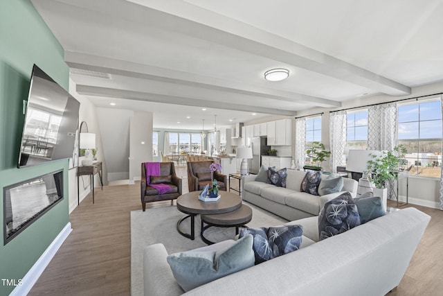 living room with beamed ceiling, light hardwood / wood-style floors, and a wealth of natural light