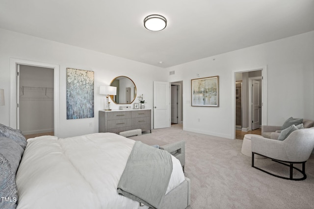 bedroom featuring light carpet, a walk in closet, and a closet