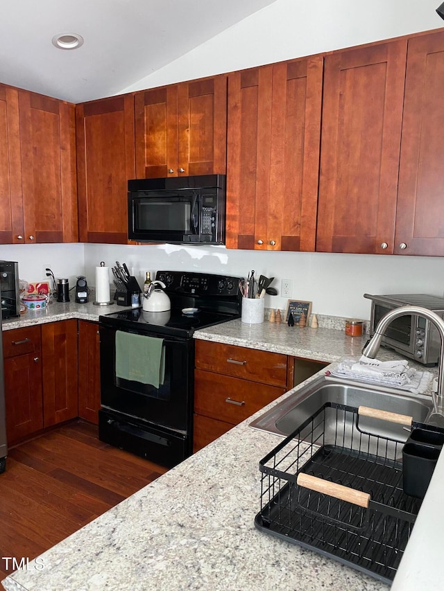 kitchen with black appliances, vaulted ceiling, light stone counters, and dark hardwood / wood-style flooring