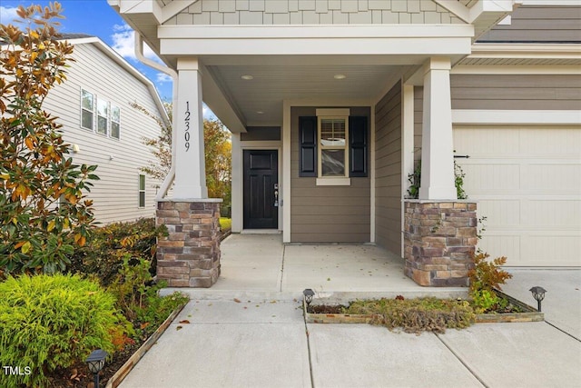 doorway to property with a garage and a porch