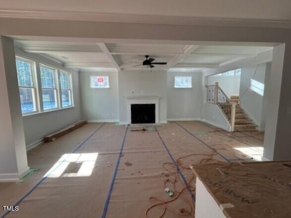 unfurnished living room with ceiling fan, beam ceiling, and coffered ceiling