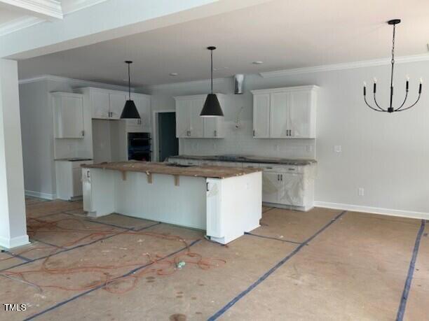 kitchen featuring decorative backsplash, black double oven, a notable chandelier, a center island, and white cabinetry