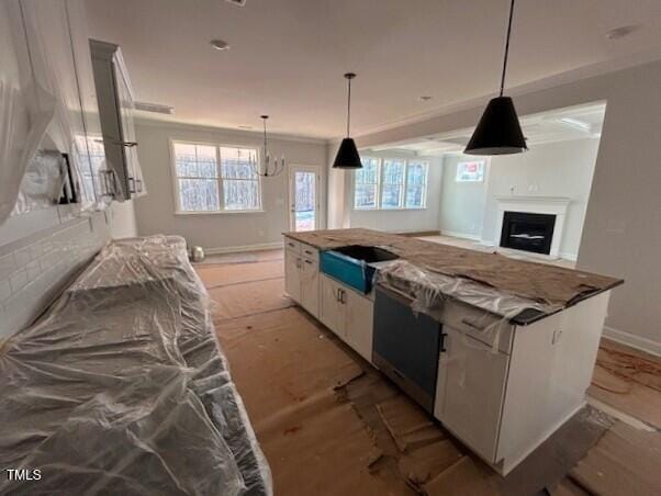 kitchen featuring white cabinetry, a center island, an inviting chandelier, light stone counters, and pendant lighting