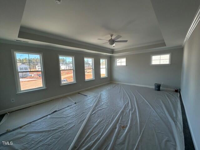 unfurnished room featuring a raised ceiling, ceiling fan, and ornamental molding