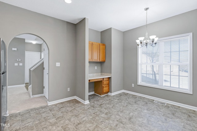 kitchen with pendant lighting, built in desk, stainless steel fridge, and an inviting chandelier