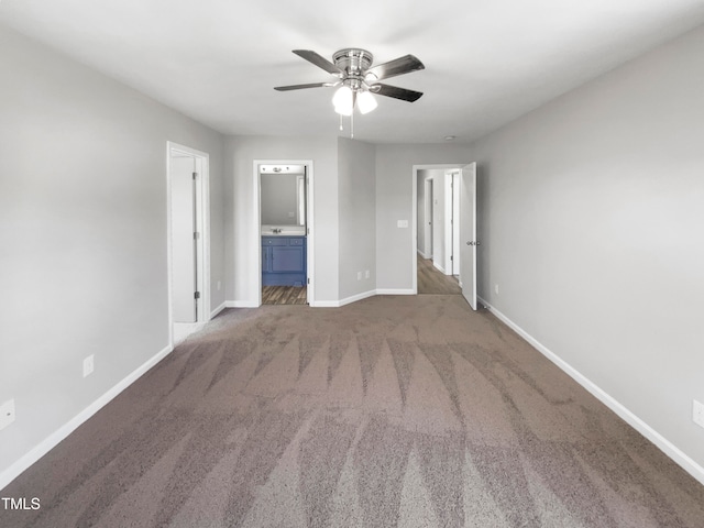 unfurnished bedroom featuring ensuite bath, dark colored carpet, and ceiling fan