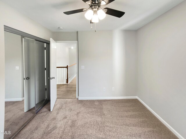 unfurnished bedroom with a closet, light colored carpet, and ceiling fan