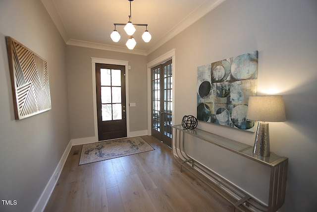 foyer featuring french doors, crown molding, wood-type flooring, and a chandelier