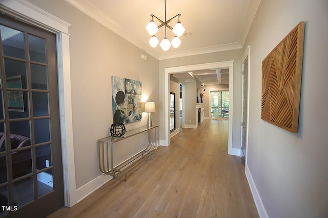 hall featuring crown molding, a notable chandelier, and light wood-type flooring