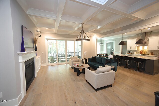 living room with light hardwood / wood-style floors, beam ceiling, and coffered ceiling