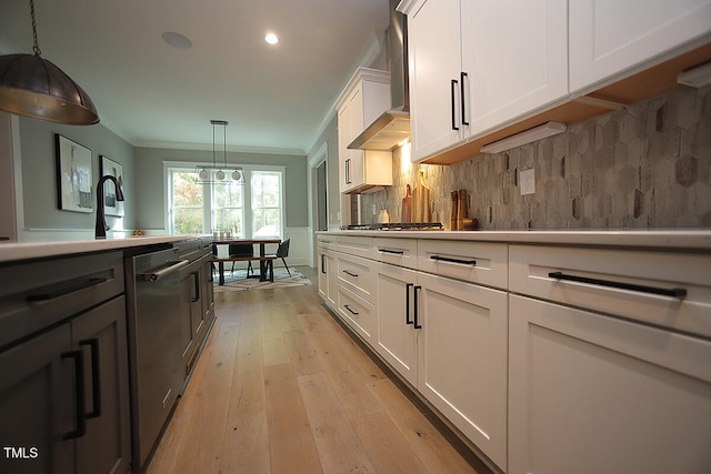 kitchen featuring crown molding, pendant lighting, light wood-type flooring, stainless steel dishwasher, and white cabinetry