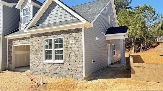 view of side of property featuring stone siding and roof with shingles