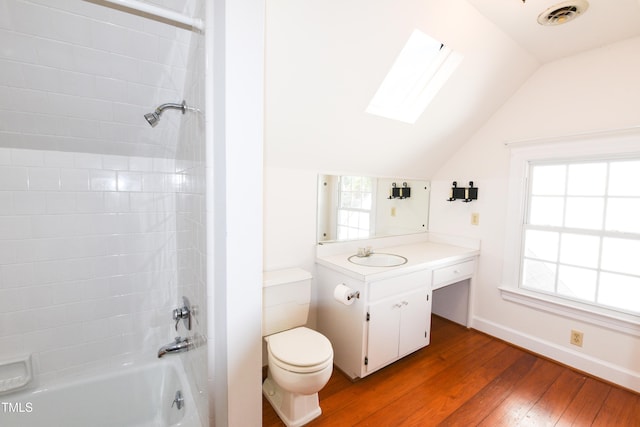 full bathroom featuring hardwood / wood-style flooring, toilet, tiled shower / bath, vanity, and lofted ceiling with skylight