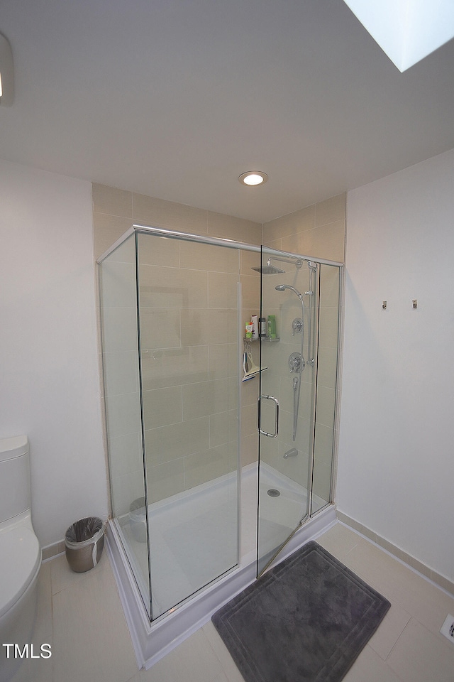 bathroom with a shower with door, toilet, and tile patterned floors