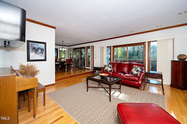 living room with light wood-type flooring, a chandelier, a textured ceiling, and crown molding