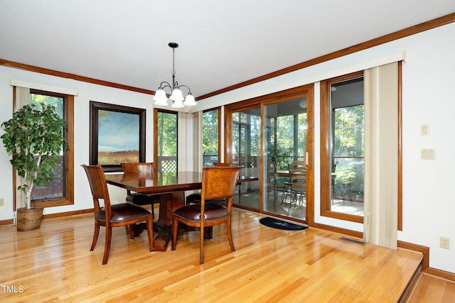 dining space with a healthy amount of sunlight, light wood-type flooring, crown molding, and a notable chandelier