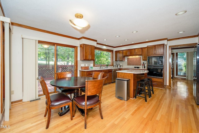 dining space with sink, crown molding, and light hardwood / wood-style flooring