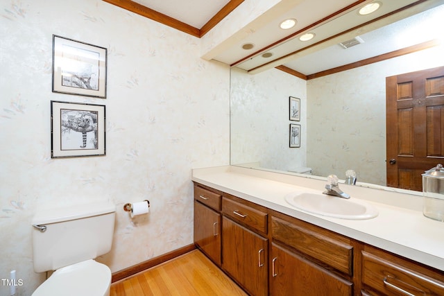 bathroom featuring toilet, vanity, hardwood / wood-style floors, and ornamental molding