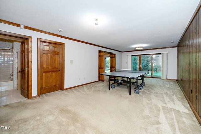 rec room with wood walls, light colored carpet, and crown molding