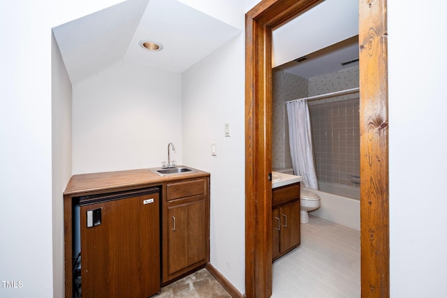 interior space featuring tile patterned floors, vanity, shower / bath combo, vaulted ceiling, and toilet