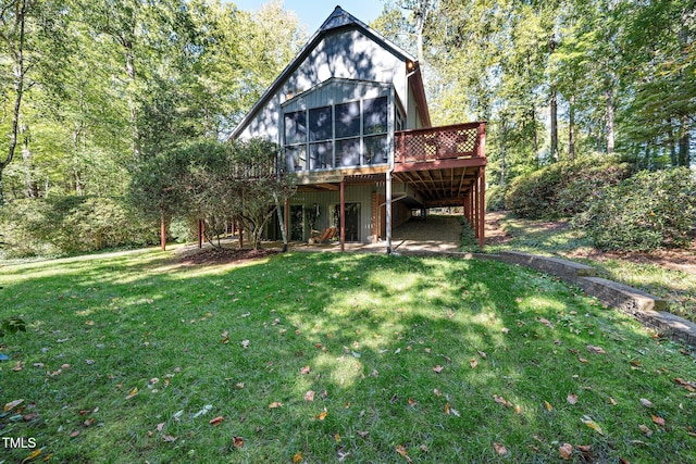 rear view of house featuring a sunroom, a lawn, and a wooden deck