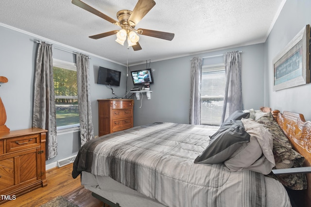 bedroom featuring ceiling fan, ornamental molding, a textured ceiling, and light hardwood / wood-style floors