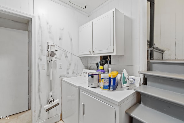 washroom featuring wood walls, ornamental molding, washing machine and clothes dryer, and cabinets