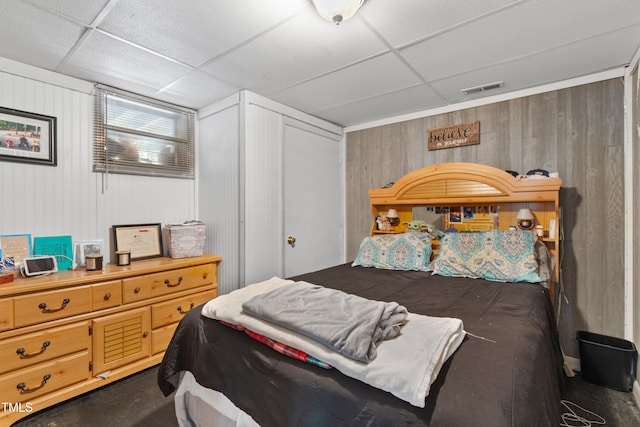 bedroom featuring a drop ceiling and wooden walls