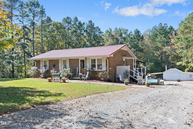 ranch-style home with covered porch, a storage shed, and a front yard