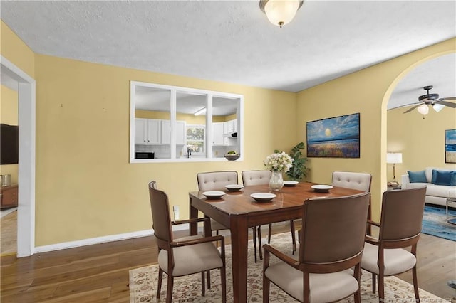 dining room featuring ceiling fan, wood-type flooring, and a textured ceiling