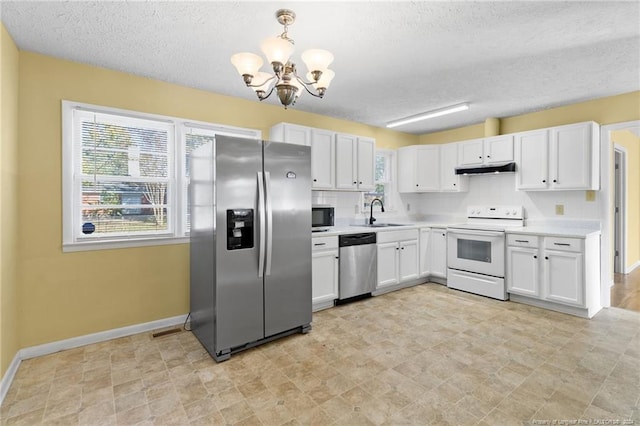 kitchen with a textured ceiling, white cabinetry, stainless steel appliances, pendant lighting, and a notable chandelier