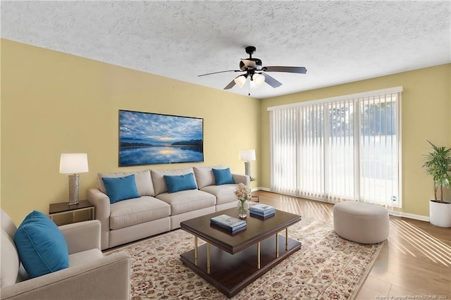 living room featuring ceiling fan, hardwood / wood-style flooring, and a textured ceiling