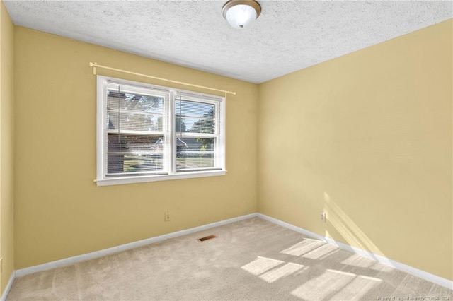 carpeted empty room featuring a textured ceiling