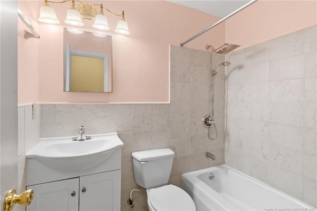 full bathroom featuring tile walls, vanity, tiled shower / bath combo, and toilet