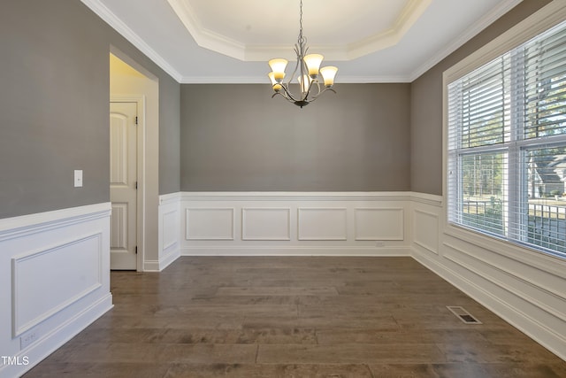 spare room with a tray ceiling, dark wood-type flooring, crown molding, and a chandelier