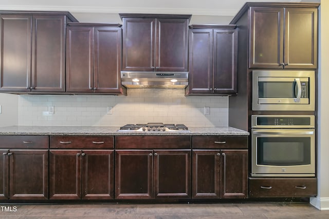 kitchen with light stone countertops, appliances with stainless steel finishes, and backsplash