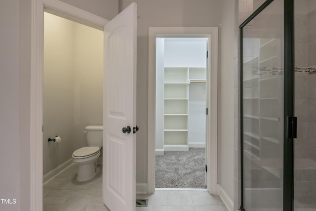 bathroom with tile patterned flooring, toilet, and walk in shower