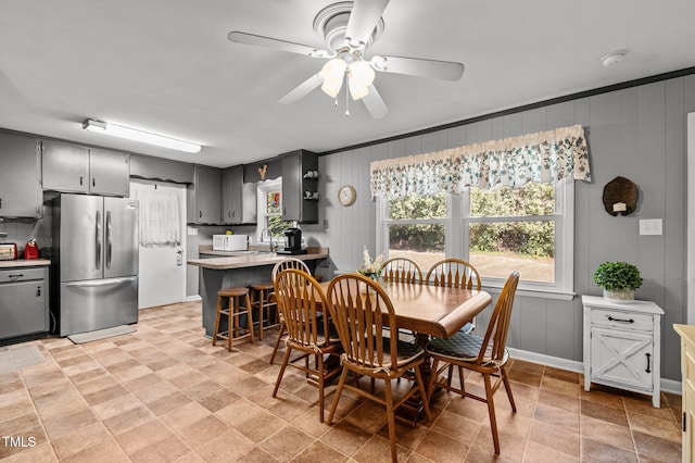 dining area featuring wood walls, sink, a barn door, ceiling fan, and ornamental molding