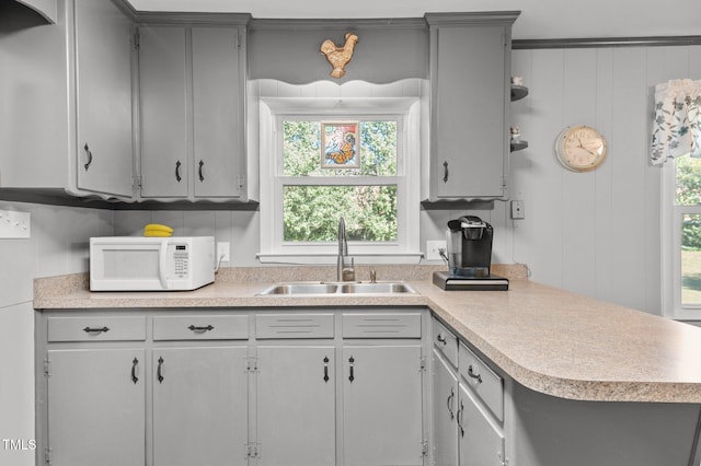 kitchen featuring gray cabinetry, a healthy amount of sunlight, sink, and kitchen peninsula