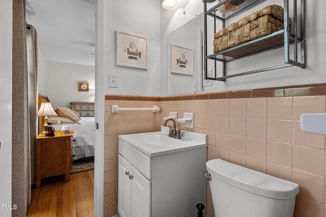 bathroom with vanity, toilet, tile walls, and hardwood / wood-style floors