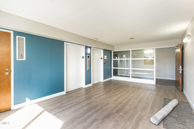 interior space with wood-type flooring and elevator