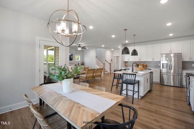 dining room with ceiling fan with notable chandelier, sink, and dark hardwood / wood-style floors