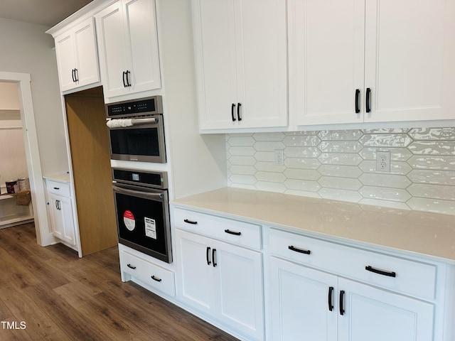 kitchen with dark wood-style floors, tasteful backsplash, white cabinetry, and stainless steel double oven