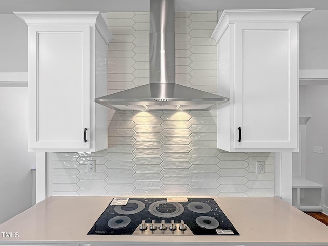 kitchen view of wall chimney exhaust hood, white cabinets, light countertops, and tasteful backsplash