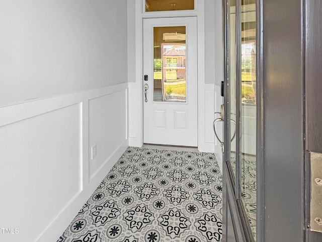 entryway featuring wainscoting, tile patterned flooring, and a decorative wall