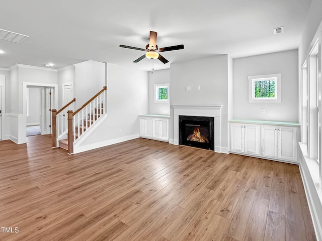 unfurnished living room with light wood-style flooring, ceiling fan, stairway, baseboards, and a high end fireplace