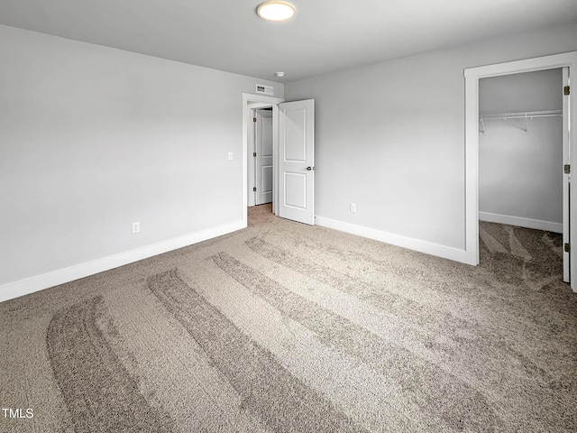 unfurnished bedroom with baseboards, carpet floors, a spacious closet, and a closet