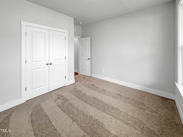 unfurnished bedroom with carpet flooring, baseboards, and a closet